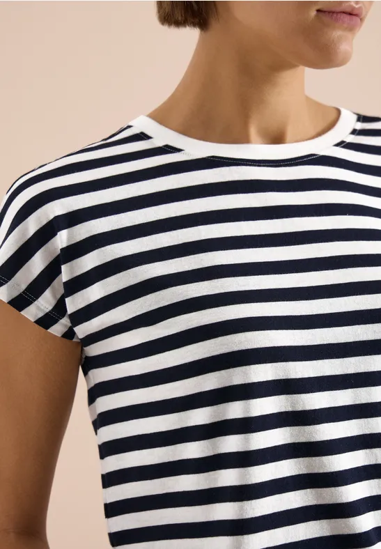 Gros plan d’une personne portant un t-shirt à rayures bleu marine et blanc.