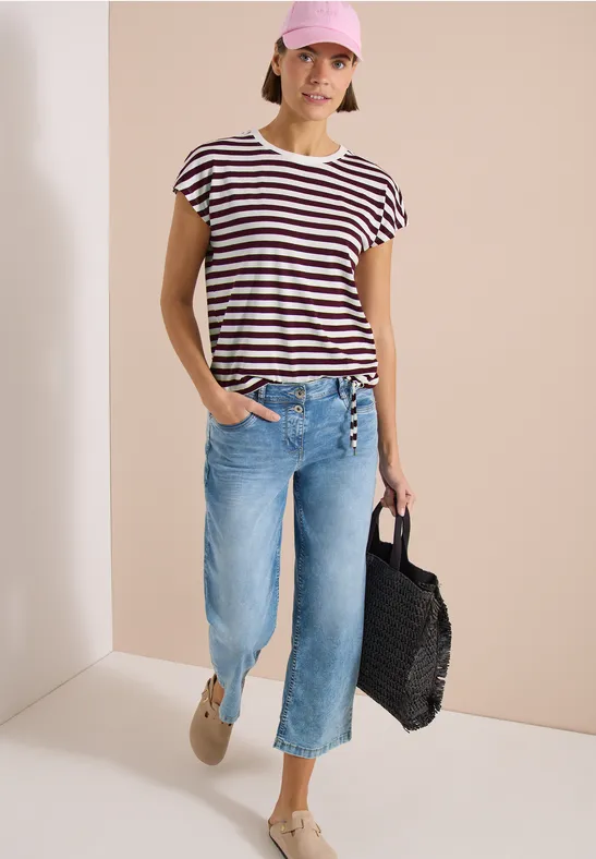 Femme en t-shirt rayé, jean culotte bleu clair, chaussures beiges et sac noir