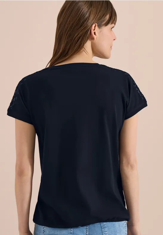 Vrouw van achteren in een zwart t-shirt voor een neutrale achtergrond.