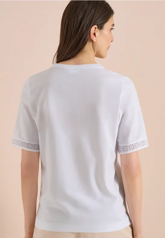 Frau von hinten in weißem Kurzarmshirt mit Spitzenbesatz an den Ärmeln.