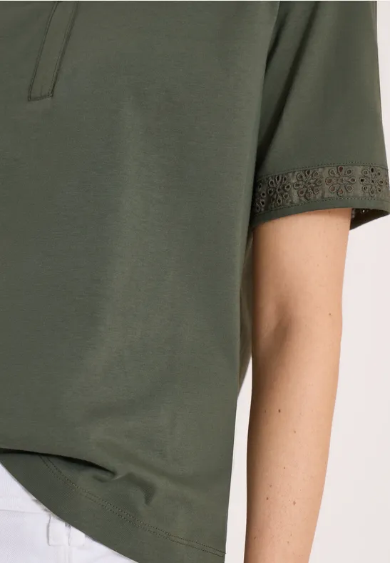 Detail van een olijfgroene korte mouw T-shirt met fijne gehaakte kant langs de mouwzoom.