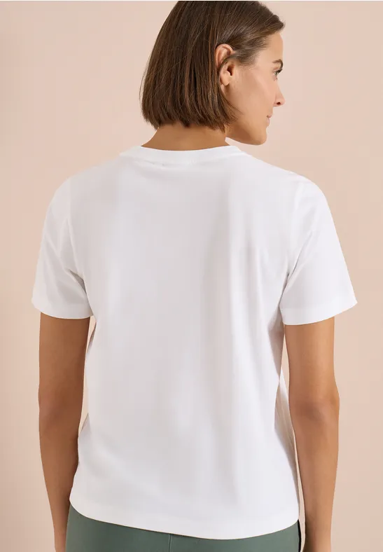 Rugaanzicht van een persoon met kort haar in een wit T-shirt tegen een neutrale achtergrond.