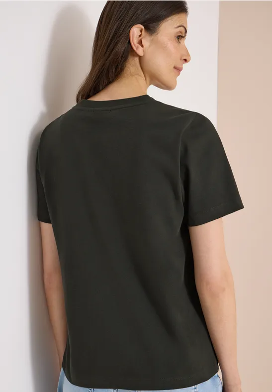 Achteraanzicht van een vrouw met een donker T-shirt met korte mouwen tegen een lichte achtergrond.