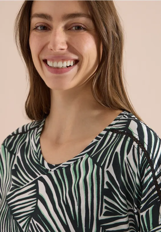 Eine Frau trägt ein grünes, schwarz-weiß gestreiftes Top mit Zebra-Muster.