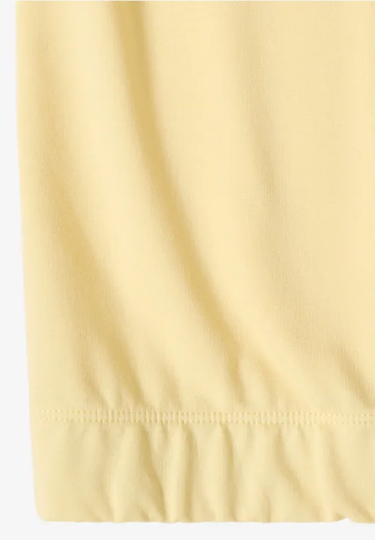 Nahaufnahme eines hellgelben, leicht gerafften Stoffsaums.