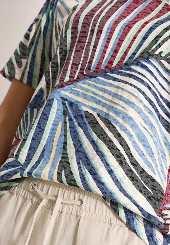 Close-up van een torso met een kleurrijk gestreept shirt en beige broek met elastische tailleband.