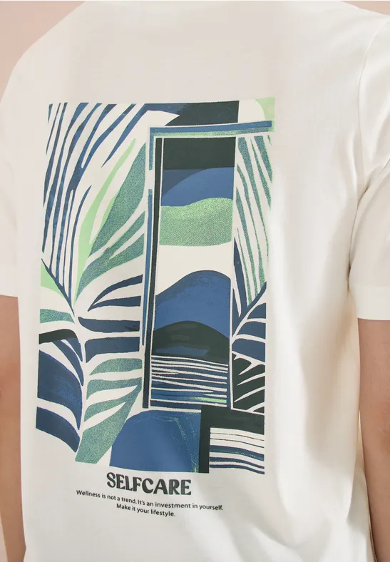 Weißes T-Shirt mit grün-blauem tropischem Blattmuster und abstraktem Fenstermotiv, Schriftzug SELFCARE