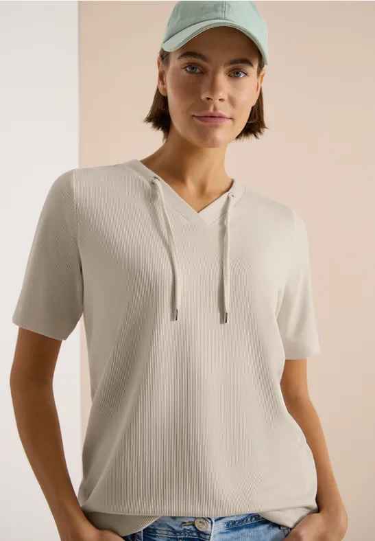 Persoon draagt lichtbeige korte mouw hoodie-shirt voor neutrale achtergrond.