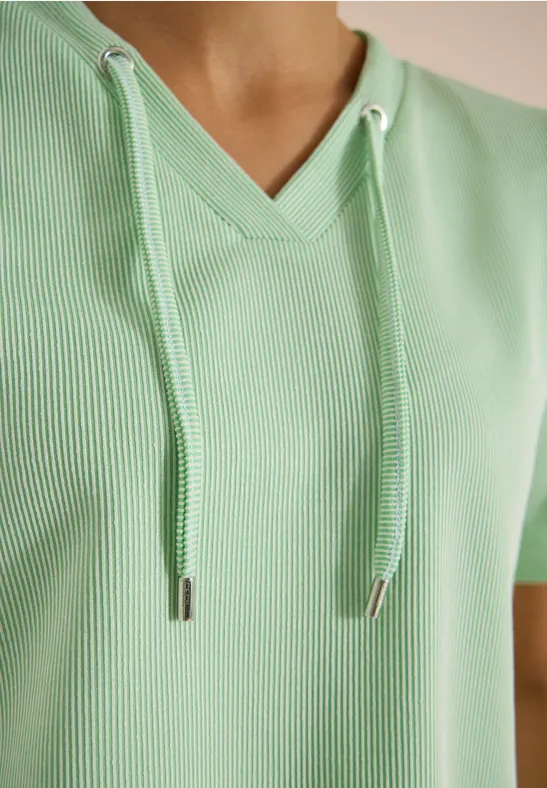 Close-up van een lichtgroene, geribbelde V-hals top met capuchonkoordjes.