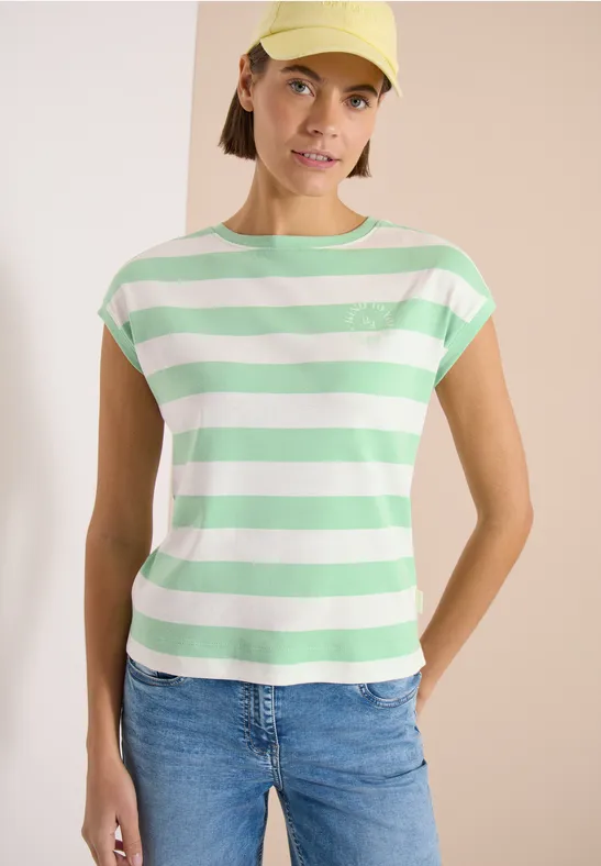 Frau in grün-weiß gestreiftem T-Shirt und Jeans vor hellem Hintergrund.