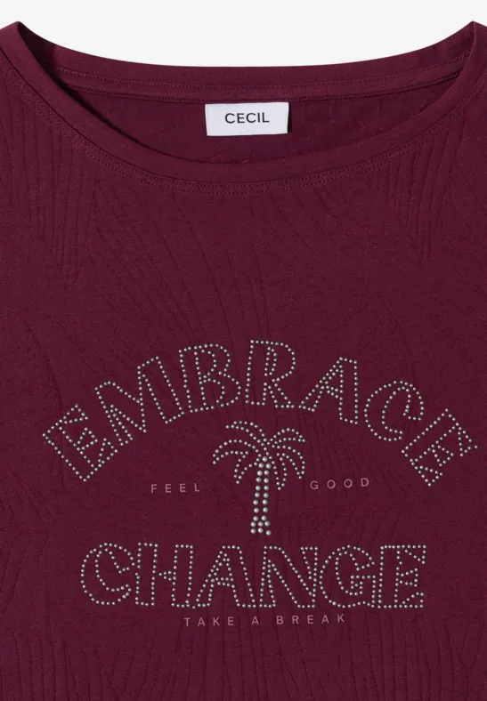 T-shirt bordeaux orné de clous formant 'EMBRACE CHANGE' et un palmier, étiquette 'Cecil' au col