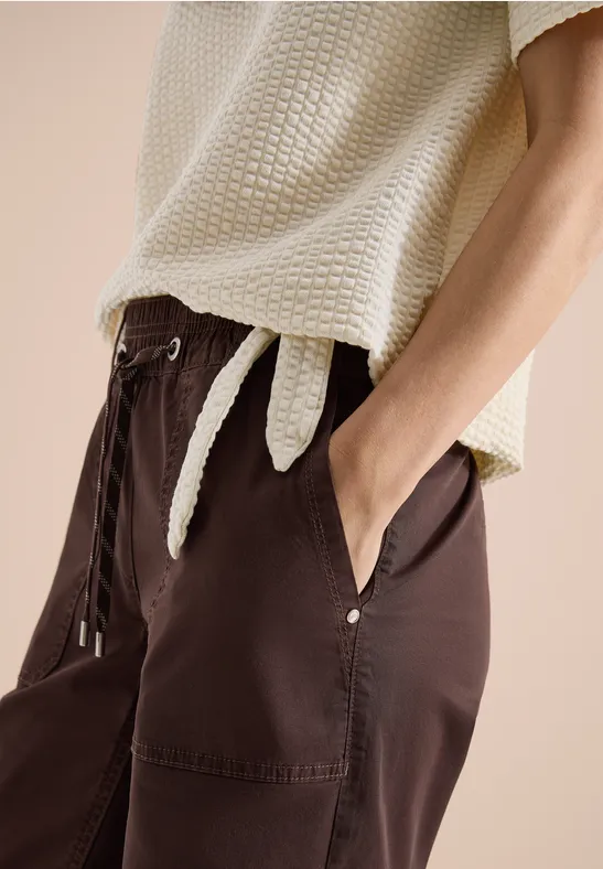 Damesoutfit met lichtbeige, gestructureerde top en losse donkerbruine broek met zakken