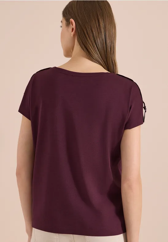 Frau von hinten in schlichtem, dunkelviolettem Kurzarmshirt.