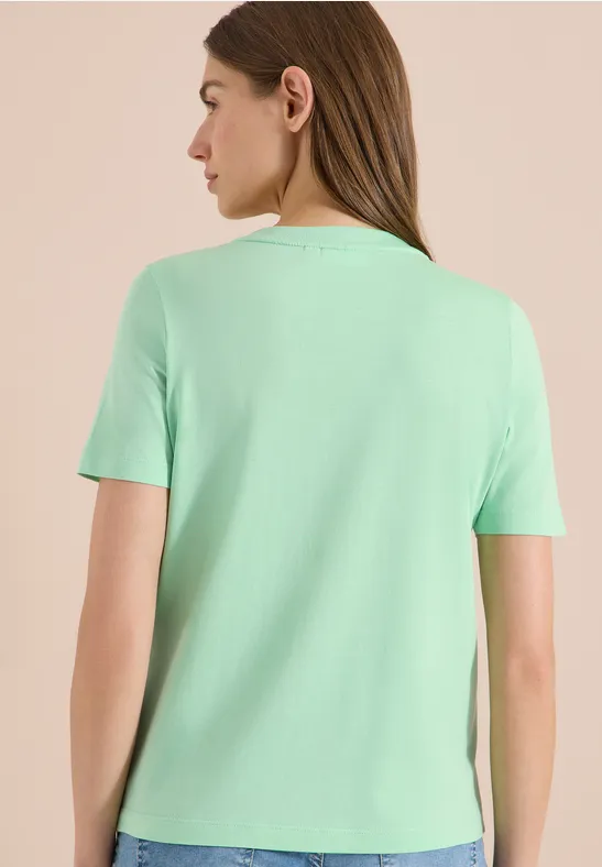 Rückansicht einer Frau in schlichtem mintgrünen T-Shirt mit kurzen Ärmeln.