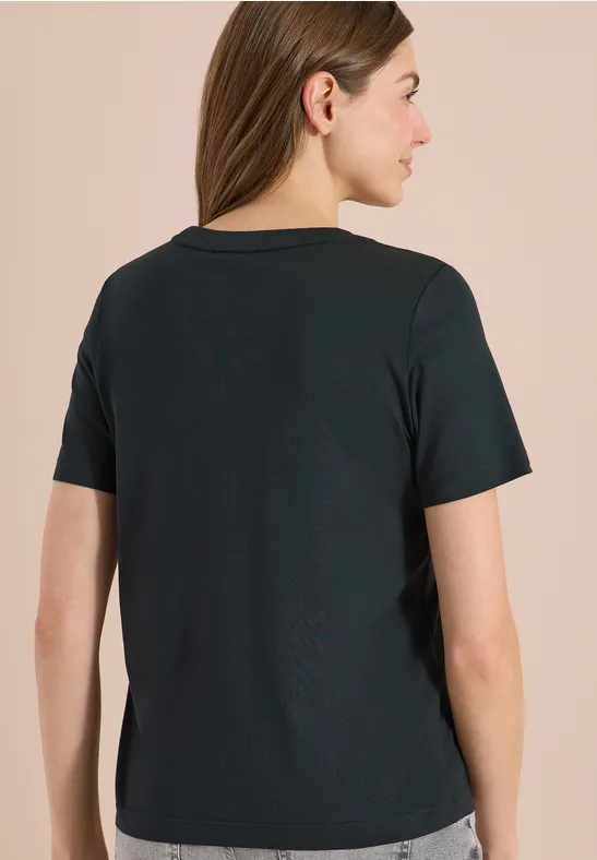 Vue de dos d’une femme portant un t-shirt noir à manches courtes sur fond beige.