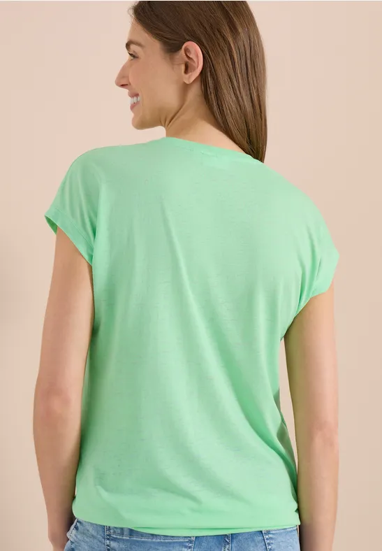 Frau von hinten mit mintgrünem T-Shirt und kurzen Ärmeln, vor neutralem Hintergrund.