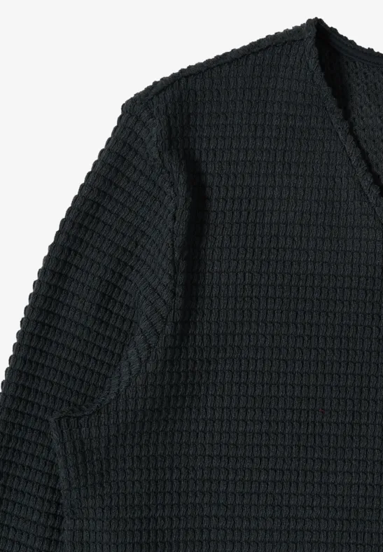 Pull noir à motif gaufré en tricot avec encolure en V.