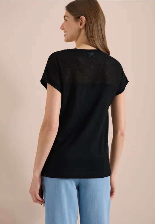 Vrouw van achteren in zwart T-shirt en blauwe spijkerbroek voor neutrale achtergrond.