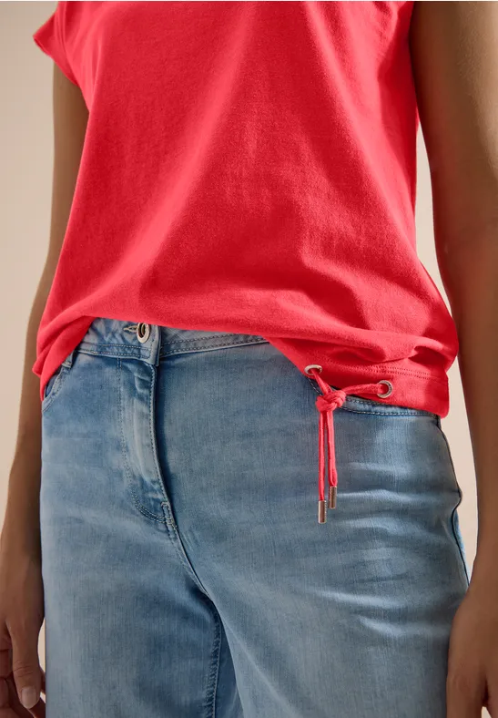 Rotes Top und lockere blaue Jeans, seitliche Oberkörperansicht