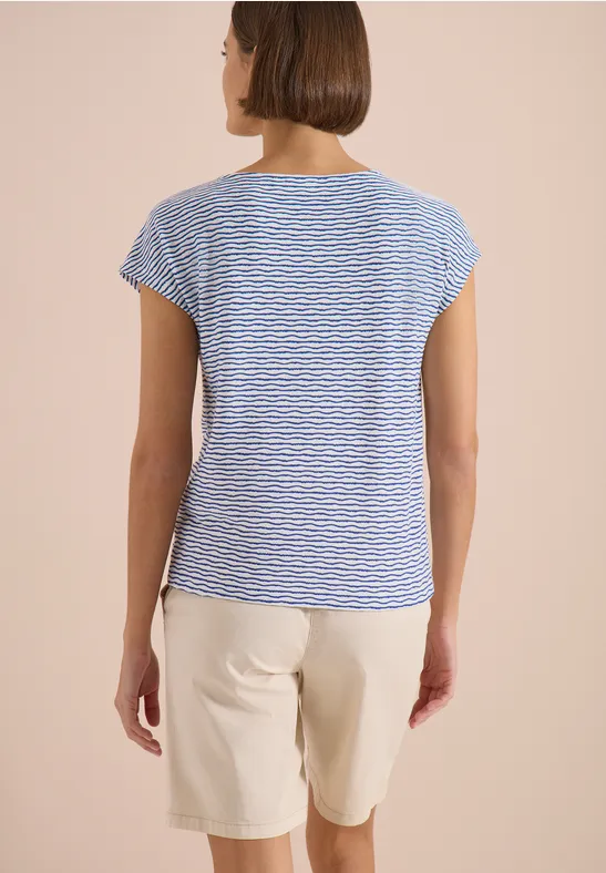 Personne vue de dos portant un t-shirt bleu-blanc rayé et un short beige sur un fond neutre.