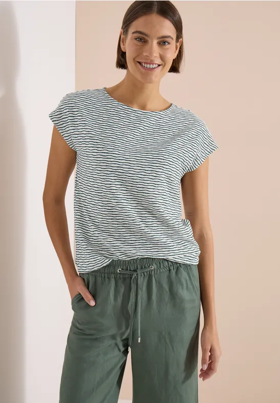 Femme porte un t-shirt rayé et un pantalon vert décontracté.