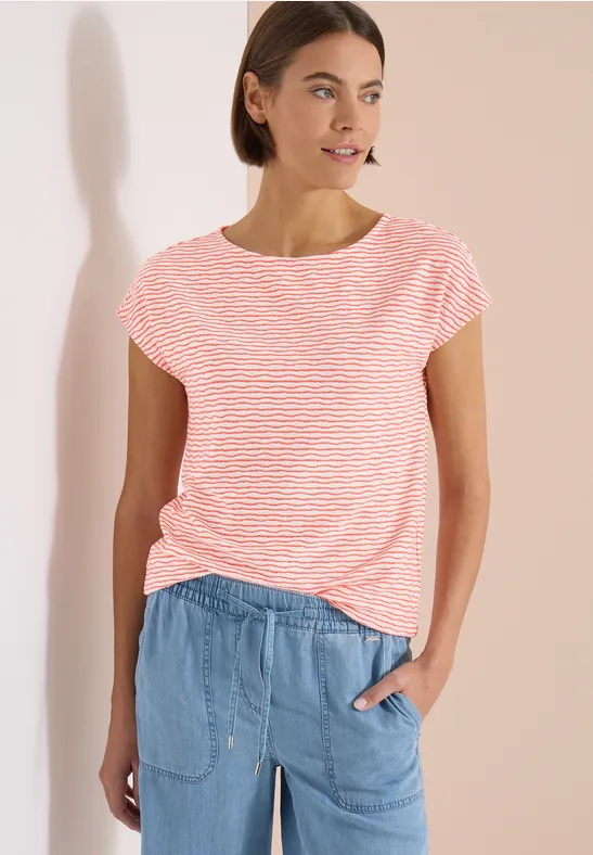 Femme en t-shirt rayé rose et blanc et pantalon jean bleu clair décontracté sur fond clair.