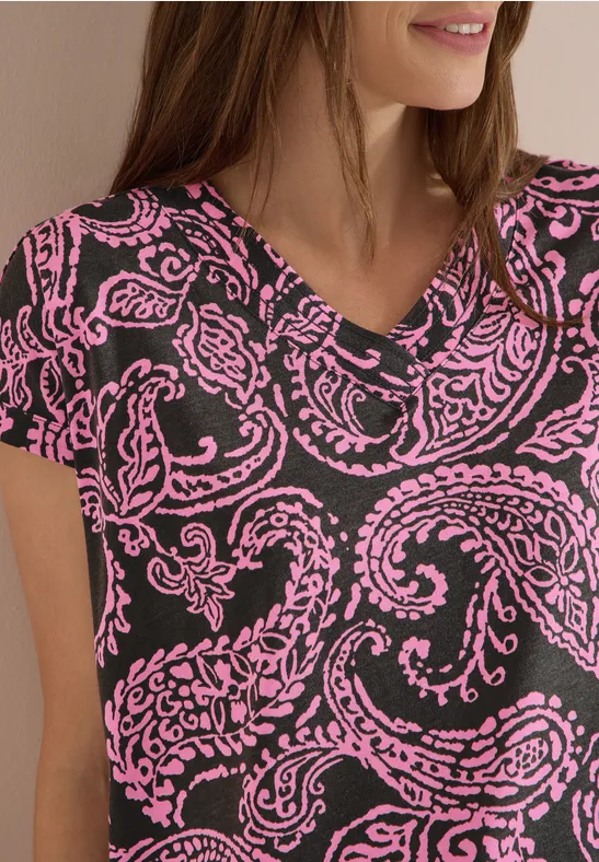 Frau in schwarzem V-Ausschnitt-Shirt mit pinkem Paisley-Muster.