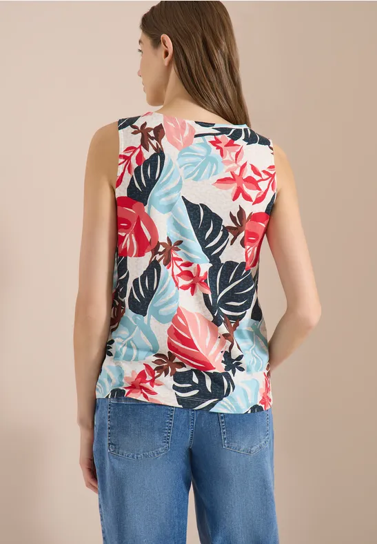 Frau von hinten in Jeans und ärmellosem Top mit buntem Blumen- und Blätter-Print.
