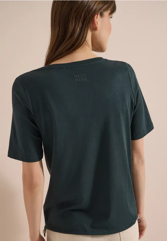 Rückenansicht einer Frau in locker sitzendem, dunkelgrünem T-Shirt mit kurzen Ärmeln und abgerundetem Saum.