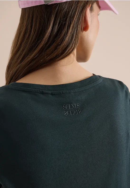 Frau von hinten mit rosa Basecap, schwarzem T-Shirt und kleinem Logo am Nacken.