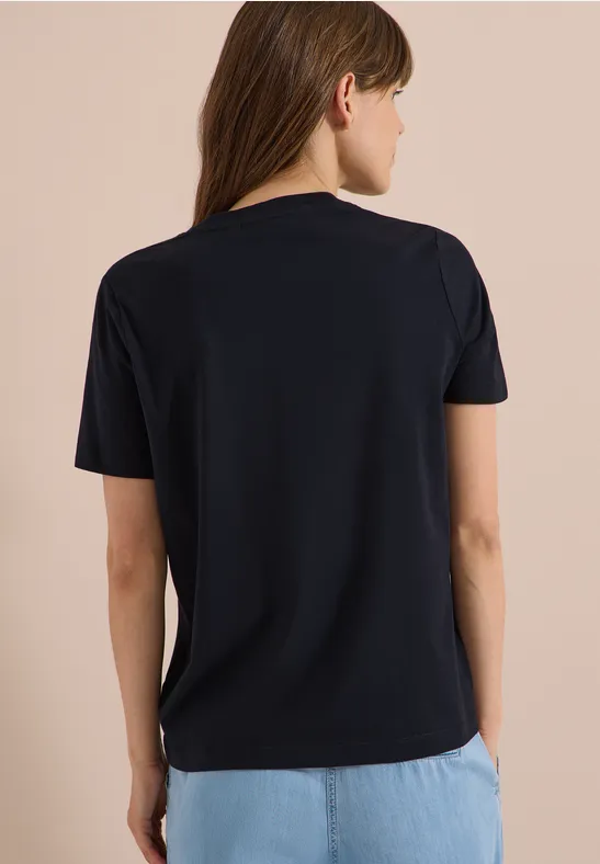 Frau von hinten in schlichten schwarzem T-Shirt und hellblauen Jeans.