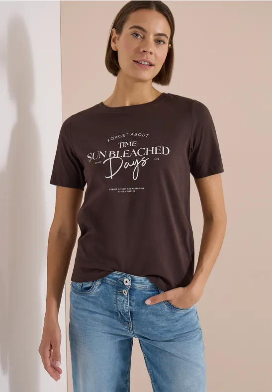 Eine Person trägt ein dunkelgraues T-Shirt mit weißem Schriftzug 'The sun bleached days' und blaue Jeans.
