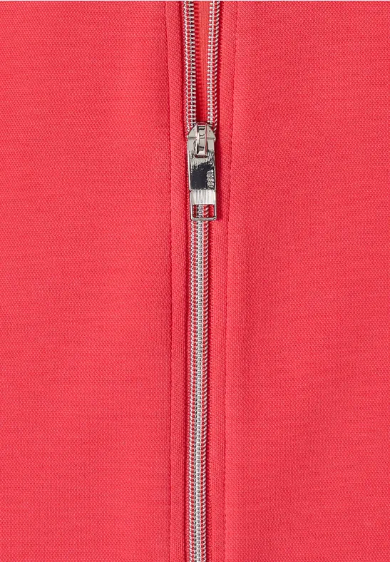 Rotes Kleidungsstück aus Stoff mit silbernem Reißverschluss in der Mitte