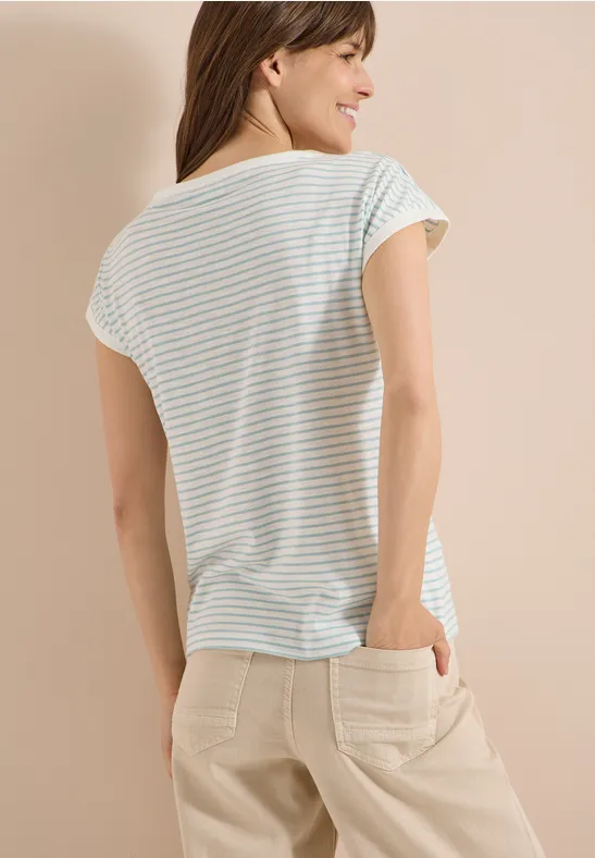 Frau von hinten in pastellgestreiftem T-Shirt und beigen Hosen mit Taschen vor hellem Hintergrund