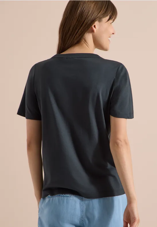 Rückansicht einer Frau mit dunkelgrauem T-Shirt und hellblauen Jeans.