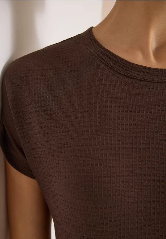Close-up van een bruin T-shirt met fijne wafelstructuur, korte mouwen en aansluitend model.