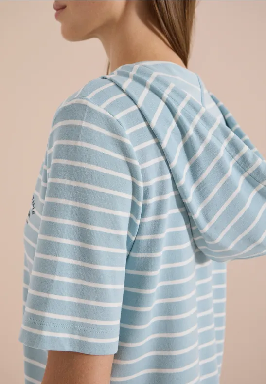 Zijaanzicht van een persoon in een lichtblauw-wit gestreept T-shirt met korte mouwen en capuchon.