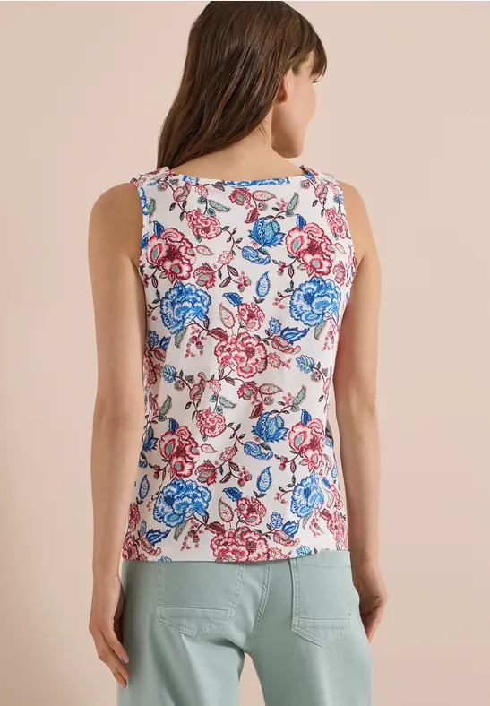 Eine Frau von hinten trägt ein ärmelloses Top mit rot-blauem Blumenmuster.