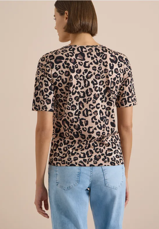 Frau von hinten in Jeans und kurzärmeligem, beigem T-Shirt mit schwarzem Leopardenmuster.
