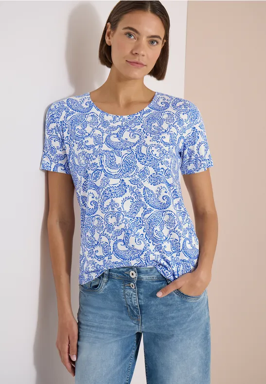 Frau in blau-weißem Paisley-T-Shirt und blauen Jeans.
