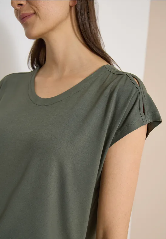 Een vrouw draagt een kaki t-shirt met een stijlvolle uitsnede bij de schouder.