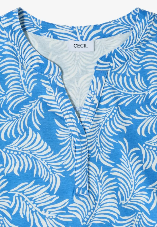 Blauw topje met wit bladmotief, V-hals en korte knoopsluiting.
