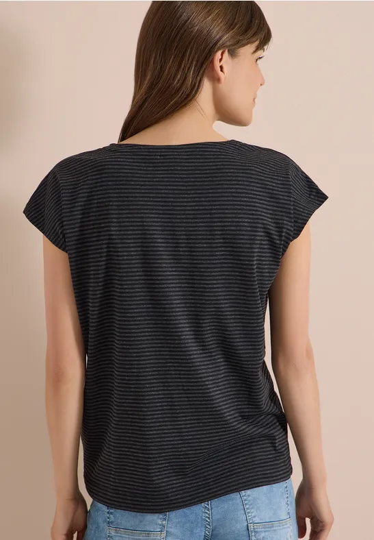 Vrouw van achteren in gestreept t-shirt en spijkerbroek voor lichte achtergrond.