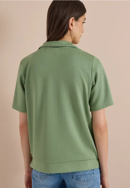 Persoon van achteren in lichtgroen poloshirt met korte mouwen en jeans