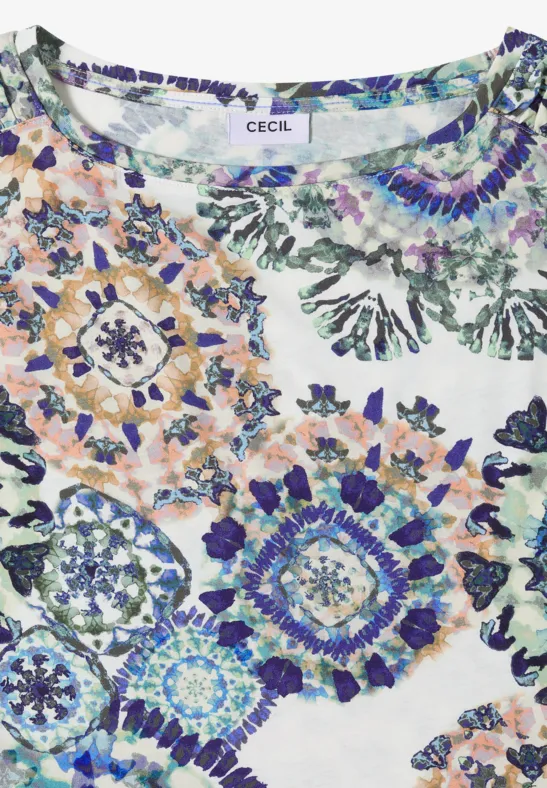 Weiße Bluse mit buntem Mosaik-Floraldruck in Blau-, Grün- und Orangetönen.