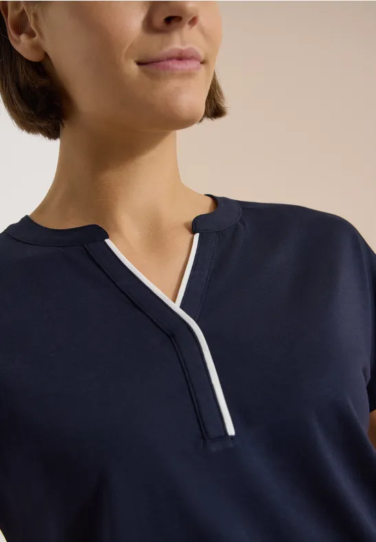 Oberkörper zeigt dunkelblaues Shirt mit V-Ausschnitt und weißer Einfassung, Kopf und Arme nicht sichtbar.