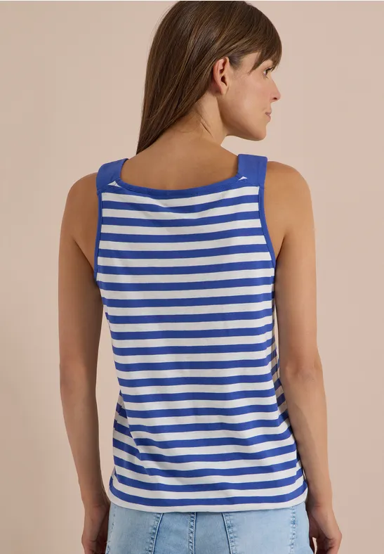 Frau von hinten in blau-weiß gestreiftem Tanktop vor beigem Hintergrund.