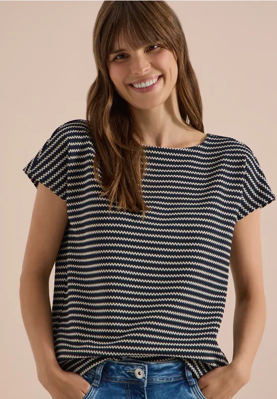 Een vrouw draagt een gestreept T-shirt met korte mouwen voor een lichte achtergrond.