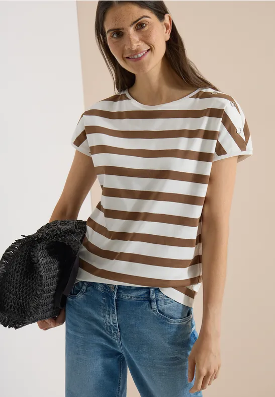 Femme en t-shirt rayé marron et blanc, jean et sac noir en paille