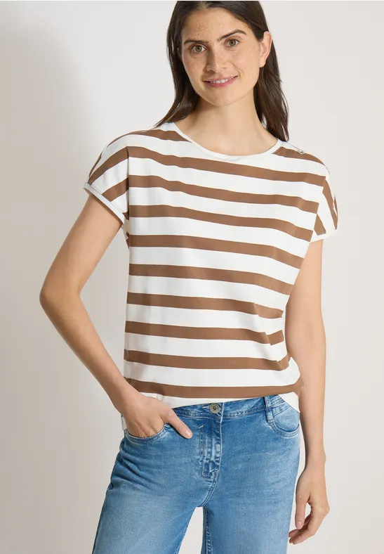 Femme portant un t-shirt court à rayures blanc et beige et un jean bleu, main dans la poche.